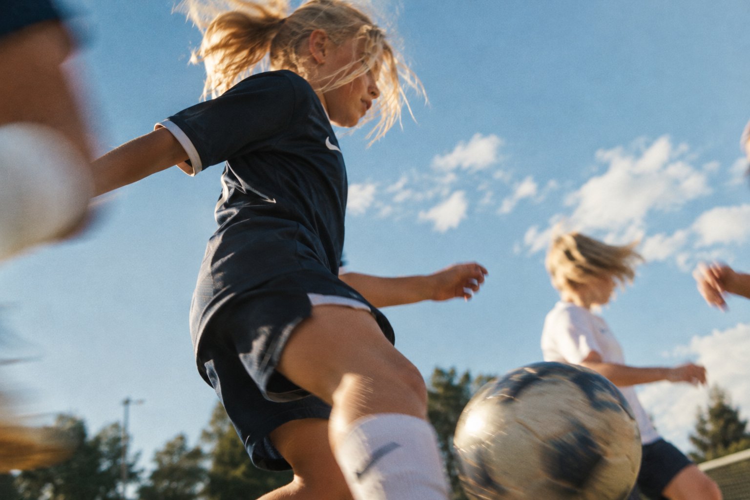 Jenter i duell om ballen på en fotballbane